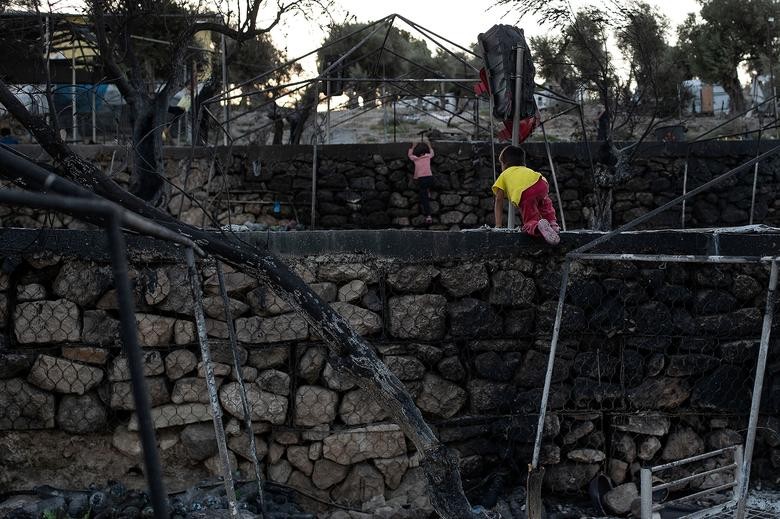 Children climb walls among burnt tents at the destroyed Moria camp for refugees and migrants, on the island of Lesbos, Greece. REUTERS/Alkis Konstantinidis  
